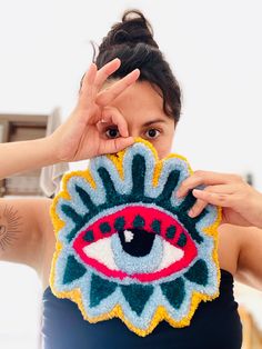 a woman holding up a knitted eye pillow to her face with both hands and fingers