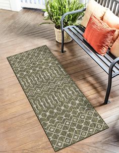 a bench sitting on top of a hard wood floor next to a green area rug