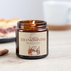 a candle sitting on top of a wooden table next to a plate with a slice of cake