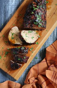 a wooden cutting board topped with ribs and potatoes on top of a blue table cloth