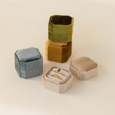 four different colored boxes with rings in them sitting on a table next to each other