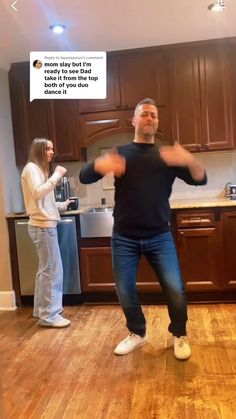 two people standing in a kitchen with one person holding his arms out to the side