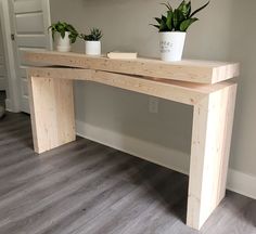 two potted plants sit on top of a wooden bench in the corner of a room