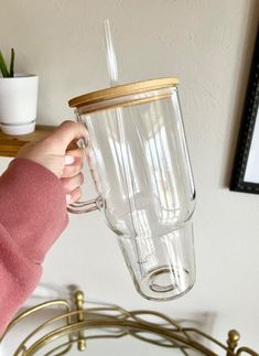 a person holding a clear glass cup in their hand