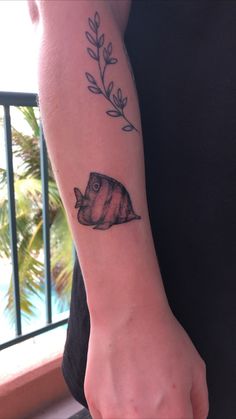 a person with a tattoo on their arm holding onto a piece of paper that has a fish on it