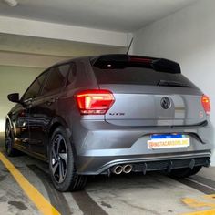 the rear end of a gray volkswagen car parked in a parking garage with yellow lines