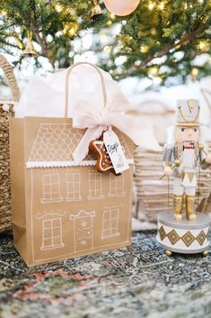 a gingerbread house is wrapped in brown paper and tied with white ribbon, next to a christmas tree