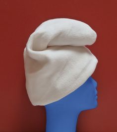 a blue mannequin head with a white hat on it's head against a red wall