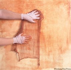 a person with white gloves on their hands is cleaning a piece of wood that has been stained orange