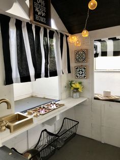 a kitchen with black and white striped curtains hanging from the ceiling, along with a gold faucet