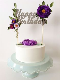 a white cake topped with purple flowers and a happy birthday sign