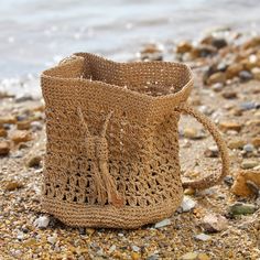 a crocheted bag sitting on top of a sandy beach