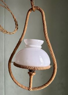 a light hanging from a rope with a white glass shade on it's side