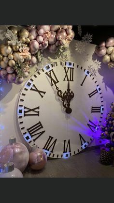 a large white clock with roman numerals on it's face next to christmas decorations