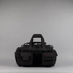 a black duffel bag sitting on top of a white floor next to a gray wall