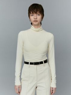 This is a turtleneck top with full-length sleeves, designed for a sleek and fitted look. The neckline is high and folds over, typical of a turtleneck style, which can provide warmth and a sophisticated appearance. The fabric appears smooth and possibly has some stretch, which would allow a close fit to the body.- The turtleneck's structure is ideal for cooler weather and can be used as a layering piece under jackets or sweaters.- Its overall design is minimalist, with no visible patterns or embellishments, offering a clean and versatile look.- The tailored fit and simple elegance make it a suitable choice for both casual and more formal settings. Neutral Turtleneck, White Turtleneck Outfit, Turtle Neck White, Turtleneck Outfit, Turtleneck Style, White Turtleneck, Turtleneck Top, 70s Inspired, Inspired Fashion