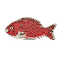 a red fish shaped brooch sitting on top of a white surface with a black outline