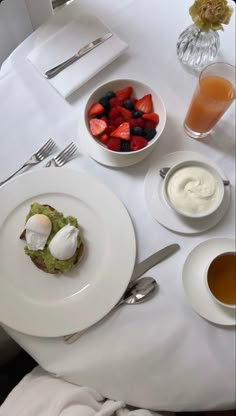 a white table topped with plates of food and cups of juice next to each other