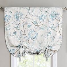 a white window with blue flowers on the valance and matching curtains in front of it