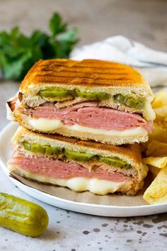 a sandwich cut in half sitting on top of a white plate next to some chips