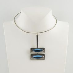 An elegant Space Age modernist collar pendant-necklace designed by Danish jewelry artist Jorgen Jensen. Made in pewter with arctic blue poured glass cabochons. Signed at the back: "Pewter - Jorgen Jensen - Denmark." Measurements: collar circumference is 16.13 in (41 cm) - pendant is 3.13 in high (7.9 cm) x 1.69 in wide (4.2 cm) - fit a Small to Medium size neck.  Please see the measurements noted above in the description for the best approximate dimensions.  About: Jorgen Jensen (b. 1931, no rel Modern Blue Necklace, Modern Metal Oval Pendant Jewelry, Modern Metal Jewelry With Oval Pendant, Modern Blue Metal Necklaces, Modern Blue Metal Necklace, Modern Blue Necklace With Polished Finish, Modern Blue Necklaces With Polished Finish, Modernist Metal Necklace With Polished Finish, Modern Cabochon Pendant Jewelry