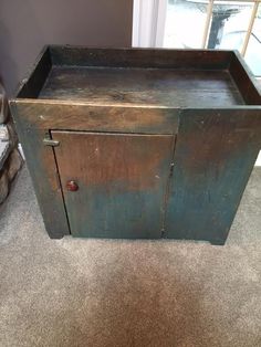 an old wooden cabinet sitting on the floor in front of a window with no curtains