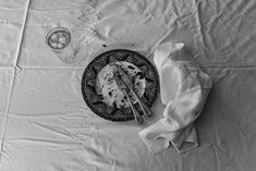 black and white photograph of plate with utensils next to napkin on table cloth