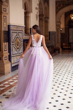 a woman in a long purple dress standing on a tiled floor with her back to the camera