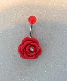 a red rose with a diamond in the center on a silver hook - end ring