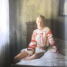 an old photo of a woman sitting on a bed