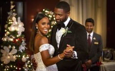 a bride and groom dancing in front of a christmas tree