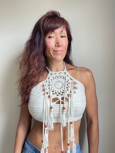 a woman with long hair wearing a crochet crop top and denim shorts posing for the camera