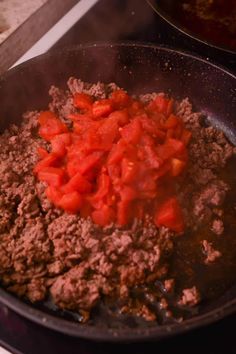 meat and vegetables cooking in a skillet on the stove top with other food items