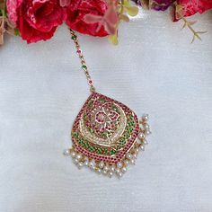 Featuring a large jadau maang teeka in 22k gold plateds sterling silver,set with precious freshwater pearls and synthetic stones that resemble rubies and emeralds. The beads in hangings are freshwater pearls. The pendant is 6cmsx5.25cms. The teeka weighs 30gms and the chain length is 8.5cms with a hook at the top Festive Gold Plated Tikka As A Gift, Bollywood Style Tikka With Intricate Design As Gift, Traditional Green Tikka For Festive Occasions, Bollywood Style Tikka With Intricate Design, Hand-set Kundan Tikka For Festivals, Hand Set Kundan Tikka For Festivals, Festive Yellow Gold Kundan Tikka, Temple Jewelry Tikka With Intricate Design As Gift, Intricate Design Tikka For Diwali Gift