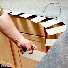 a man is holding the edge of a kitchen cabinet door with tape and sandpaper