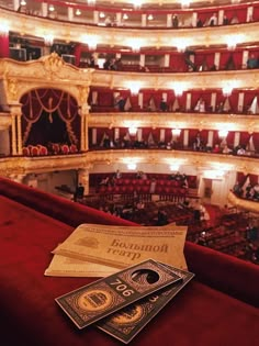 two tickets sitting on top of a red table in front of an auditorium filled with people