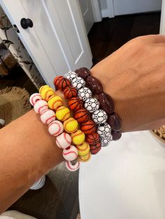 a woman's arm with four bracelets on it, each decorated with different colored balls