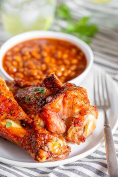 two pieces of chicken on a plate with beans