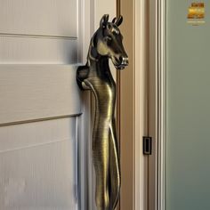 a metal horse standing on its hind legs next to a white door with gold trim