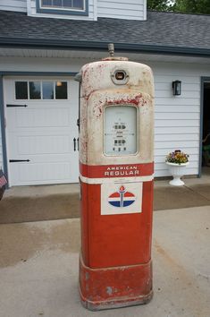 an old red and white gas pump in front of a house