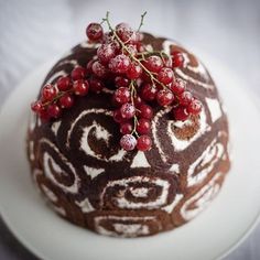 a close up of a cake on a plate with berries on top and an ornamental design