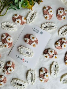 crocheted flowers and pins are arranged on a sheet of paper next to a card