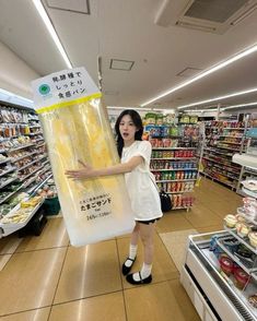 a woman is standing in a grocery store holding a plastic bag with food inside it