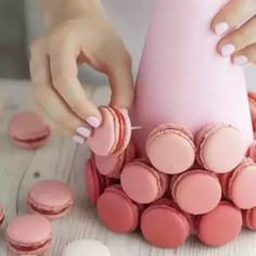 a woman is decorating pink and white macaroons