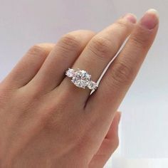 a woman's hand with a diamond ring on top of her finger, showing the side stones