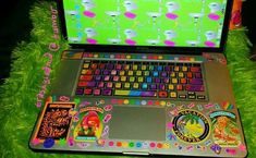 an open laptop computer sitting on top of a green grass covered field with stickers