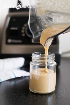 someone is pouring peanut butter into a jar