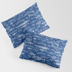 two blue pillows with fish on them, one has a white outline and the other is black