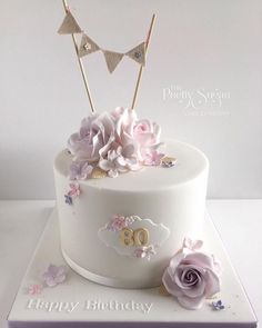 a white birthday cake with pink flowers and bunting