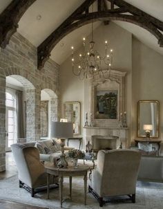 a living room filled with lots of furniture and a chandelier hanging from the ceiling